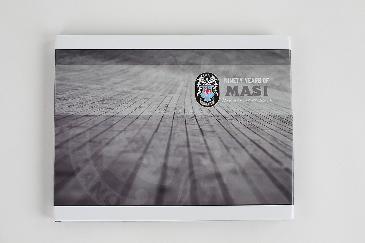 The 90 YEARS OF MASI book by Masi Bikes, with its textured gray cover and abstract line patterns, captures the essence of European bicycle racing history.