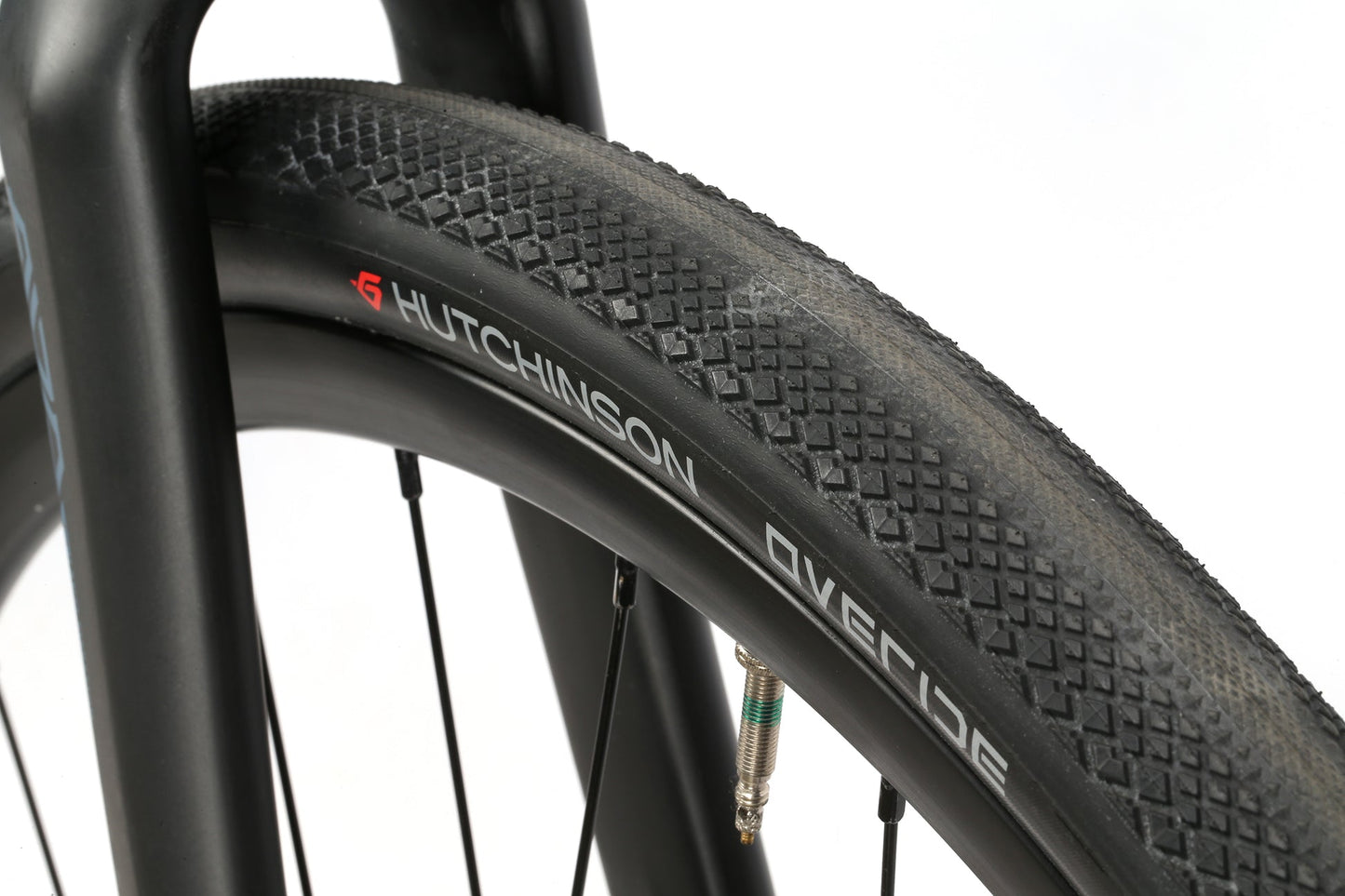 Close-up of a black Hutchinson Overide tire on a BRUNELLO ADX aluminum gravel frame with a full carbon fork.