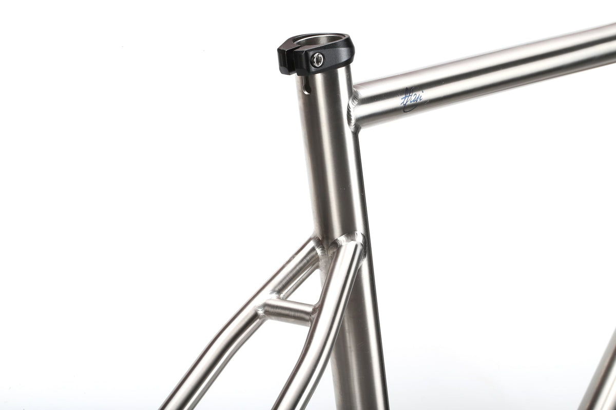 Close-up of the TITANIO FRAME's titanium seat tube and top tube, shown against a white background.