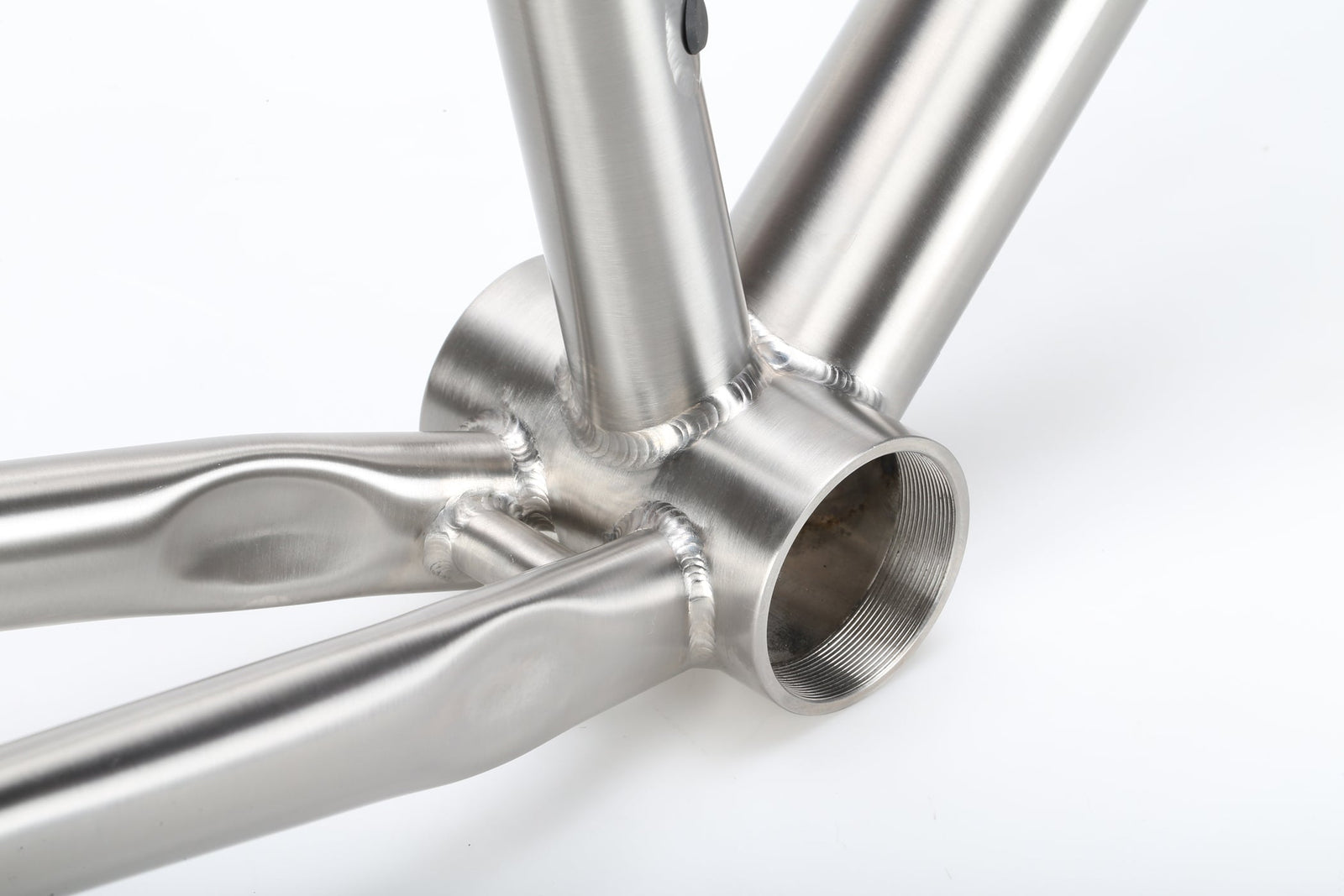 Close-up of the TITANIO FRAME’s titanium bottom bracket and welded joints against a white background.