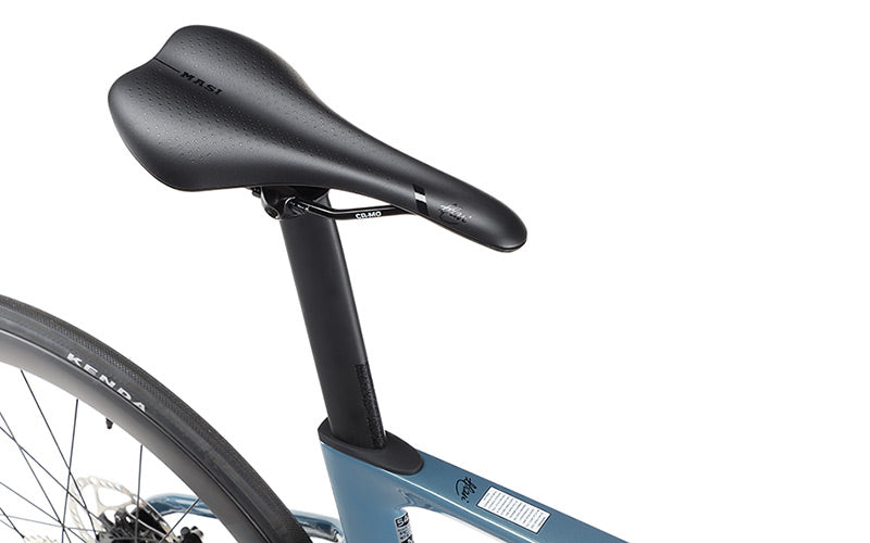 Close-up of a black saddle on a sleek, gray Masi Bikes EVOLUZIONE 1 carbon frame. Partially visible rear wheel highlights its Kenda tire. This minimalist road bikes aerodynamic design makes it ideal for speed enthusiasts.