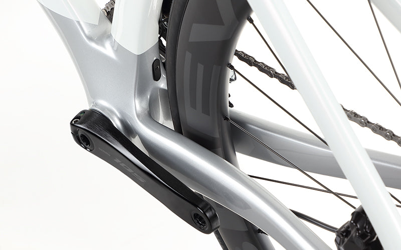 Close-up of the Masi Bikes EVOLUZIONE 1 Carbon road bike frame highlighting its aerodynamic silver and white design, focusing on the rear wheel with visible chain and black spokes.