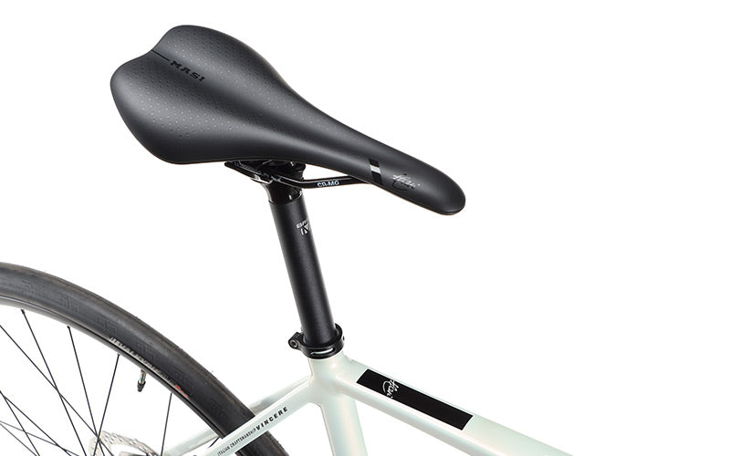 Close-up of a VINCERE 4 by Masi Bikes: a black saddle on a sleek alloy frame with internal cable routing. The rear wheel is partially visible against a white background, showcasing the modern design of the bike seat and seat post.