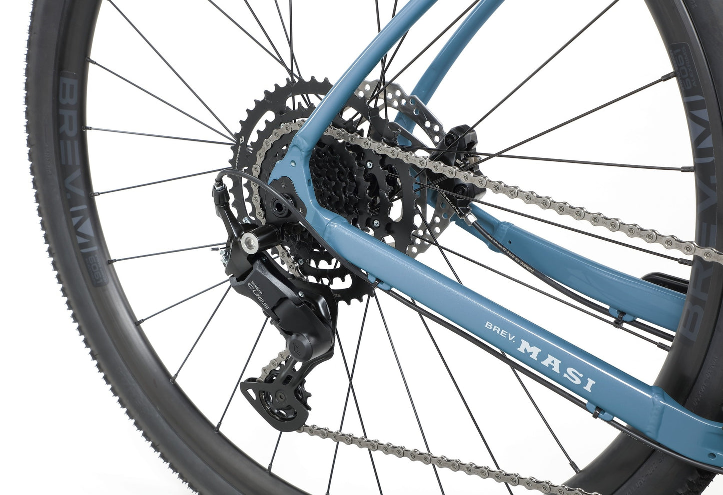 Close-up of the rear wheel, gears, chain, and derailleur of a blue BRUNELLO 3 gravel racing bike against a white background.