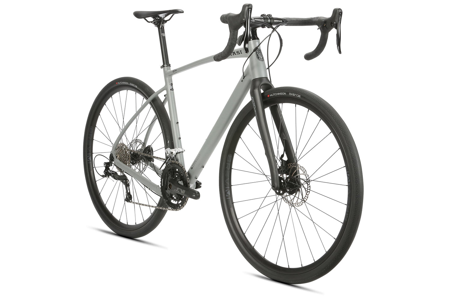 The BRUNELLO R10 is a sleek gray road bike with carbon fork, drop handlebars, black tires, and disc brakes, seen from the front.