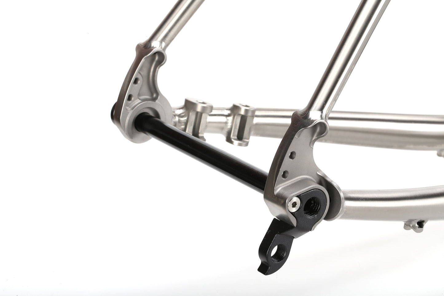 Close-up of the INCANTO Ti FRAMESET dropout by Masi Bikes, featuring silver titanium with a black axle. The precise machining and mounting points emphasize craftsmanship and engineering detail typical in 3AL/2.5V tubing for gravel bikes.