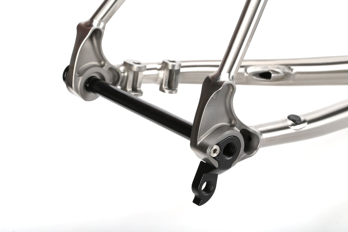 Close-up of a TITANIO FRAME titanium dropout with thru-axle, showing sleek metallic details on a white background.