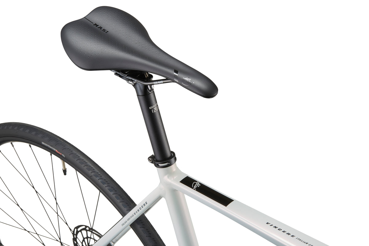 Close-up of a sleek black saddle and rear wheel on a Masi VINCERE 3 alloy frame with visible tire tread.