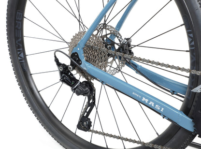Close-up of BRUNELLO 1’s rear wheel, showing tubeless-ready wheels, gears, chain, and MASI and BREV logos on the alloy frame.