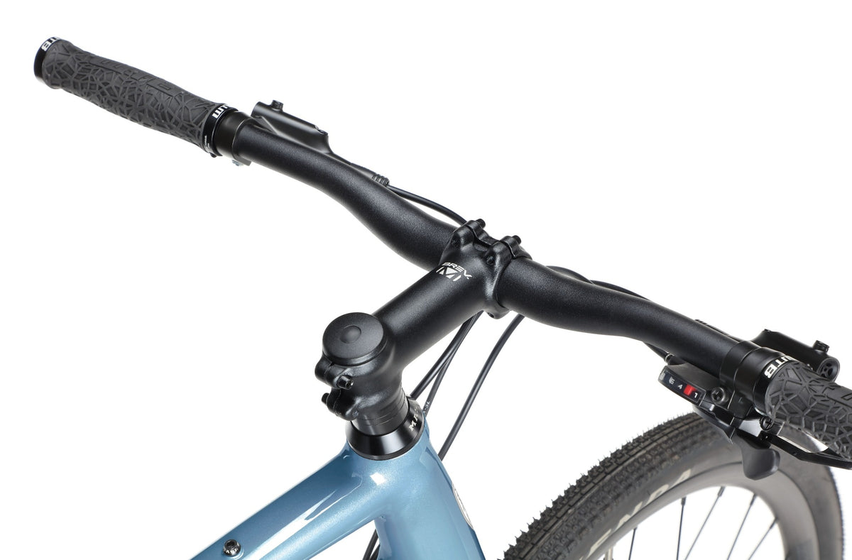 Close-up of BRUNELLO 3s black handlebar, grips, and stem on a blue frame with front tire visible against a white background.