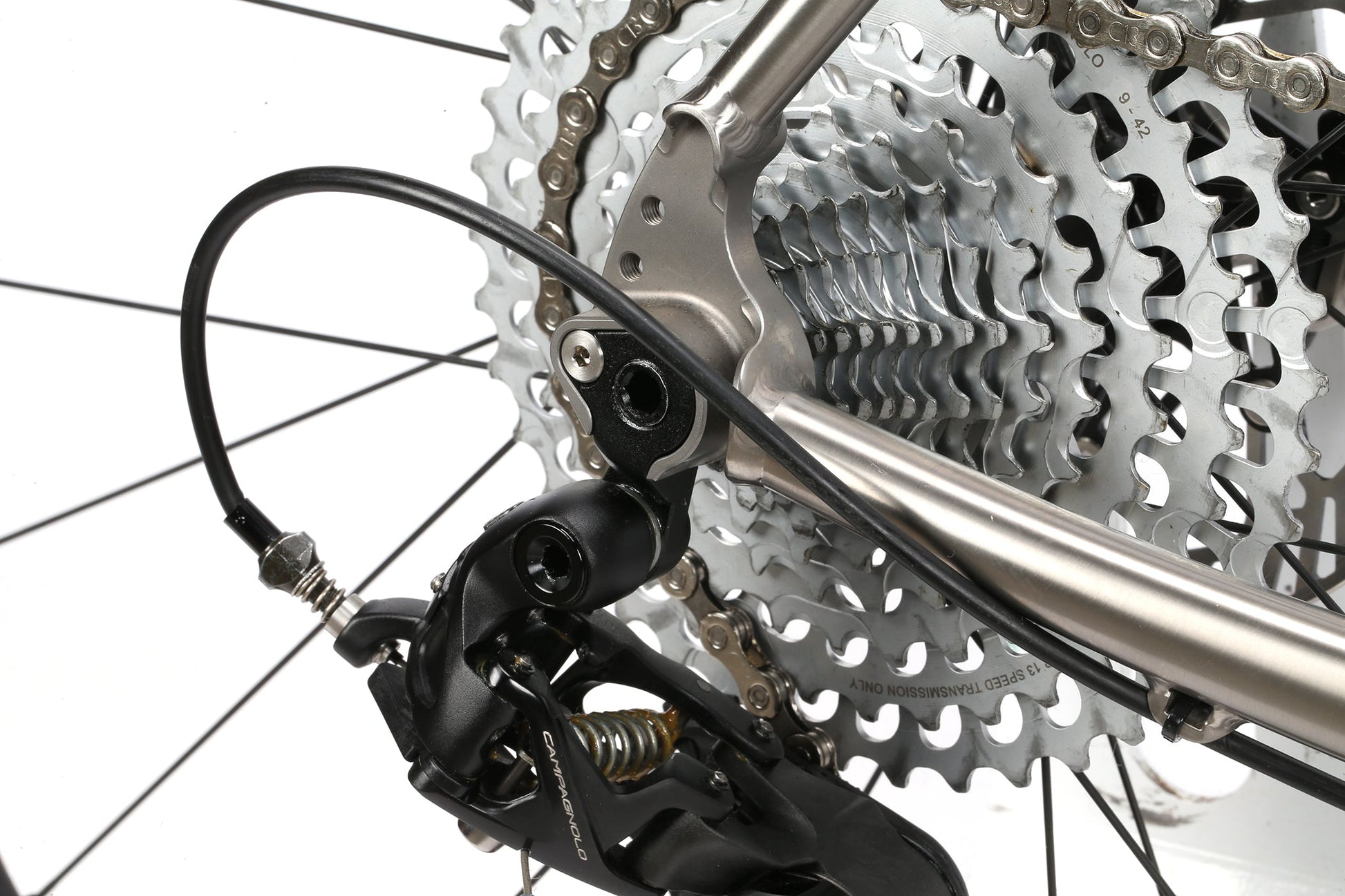 A close-up of the INCANTO CAMPY EKAR Ti by Masi Bikes showcases its gleaming Campagnolo EKAR 13-speed gears and black derailleur, expertly designed for efficient shifting. Titanium spokes radiate from the hub.