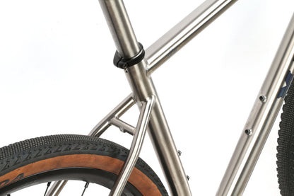 Close-up of the INCANTO CAMPY EKAR Ti by Masi Bikes, showcasing a titanium frame with smooth joints and visible seat post clamp. Features a rear tire with textured black tread and brown sidewall, along with precision Campagnolo EKAR 13-speed components.