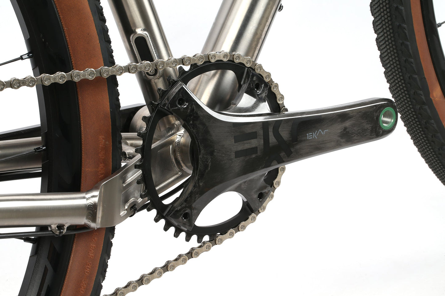 Close-up of the INCANTO CAMPY EKAR Ti by Masi Bikes, highlighting a titanium frame and Campagnolo EKAR 13-speed chain. The crank arm features its logo, while the brown-sidewall tires and all other parts showcase a new Carbon Coefficient RR design.