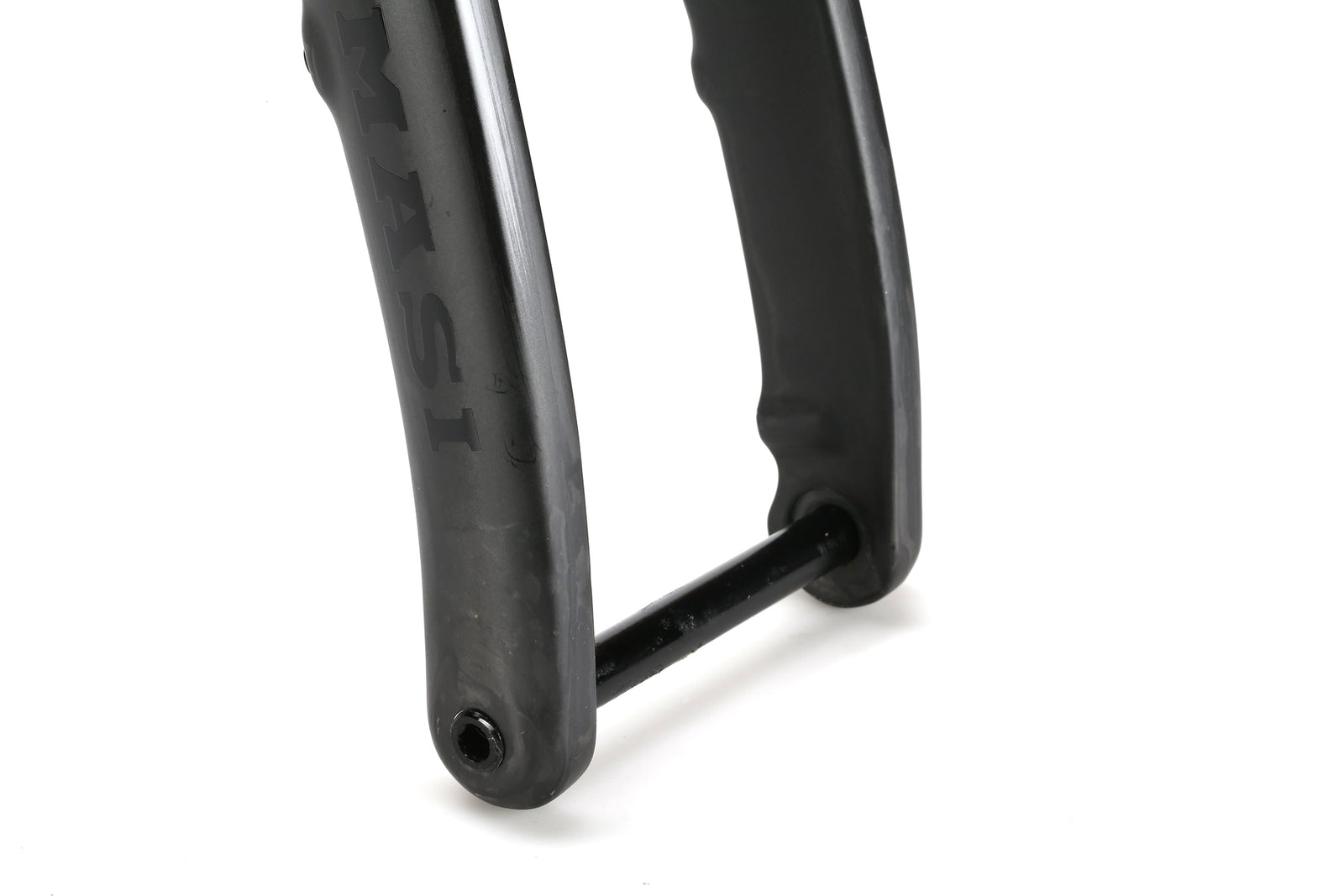 Close-up of titanium bicycle fork dropout with through axle on the Masi Bikes INCANTO Ti FRAMESET. The black fork has a slight sheen, features 3AL/2.5V tubing, and displays part of the brand name MASI. The cylindrical axle is centered on the gravel bikes frame.